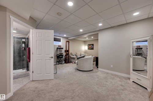 Recessed lighting illuminates the carpeted living area with a drop ceiling - 2203 Warry Loop Sw, Edmonton, AB 