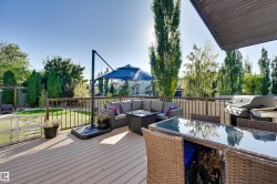 Expansive outdoor deck featuring composite decking, dark railings, and a built-in outdoor kitchen area - 