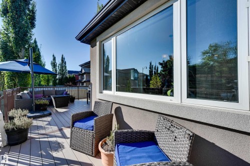 Spacious composite deck with dark metal railing, featuring a stucco exterior and large window - 2203 Warry Loop Sw, Edmonton, AB 