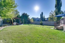 Expansive backyard featuring a manicured lawn, established trees, and a wooden pergola - 