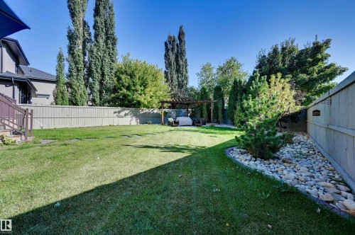 Expansive backyard with a manicured lawn, established privacy fencing, and mature trees - 2203 Warry Loop Sw, Edmonton, AB 