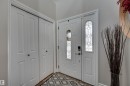 Entryway with a white paneled door featuring decorative glass inserts, a white paneled sidelight, and double bi-fold closet doors - 2203 Warry Loop Sw, Edmonton, AB 