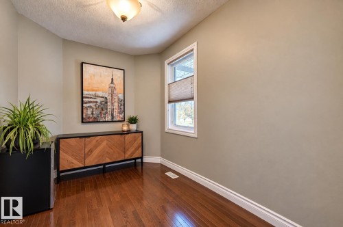 Hardwood flooring, neutral wall tones, window with natural light, white trim, and a ceiling-mounted fixture - 2203 Warry Loop Sw, Edmonton, AB 