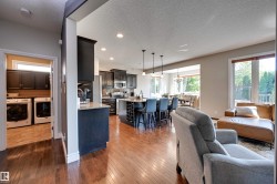 Hardwood-style flooring throughout, dark wood-finish cabinetry, recessed ceiling lights, an integrated wine rack, and a built-in laundry area with overhead storage - 