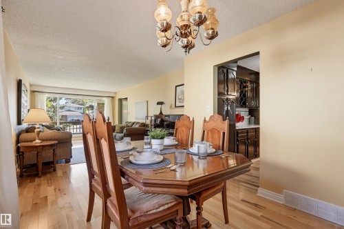 Wood-finish flooring throughout, decorative chandelier, and a framed opening to the kitchen - 30 Gariepy Crescent Nw, Edmonton, AB 