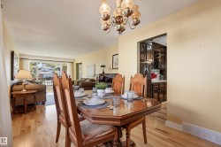 Wood-finish flooring throughout, decorative chandelier, and a framed opening to the kitchen - 