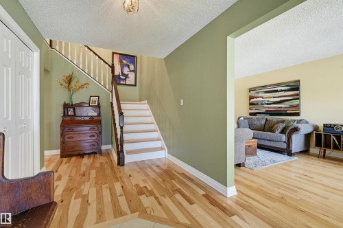 Hardwood flooring, painted walls, white trim, and a staircase with white risers and dark wood handrail - 30 Gariepy Crescent Nw, Edmonton, AB 