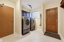 Laundry area featuring floor-to-ceiling cabinetry, a front-loading washer and dryer, and a window - 
