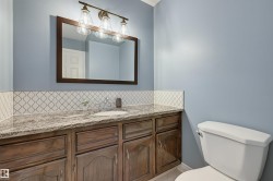 Vanity with wood-finish cabinetry, stone countertop, integrated sink, and an arabesque tile backsplash - 