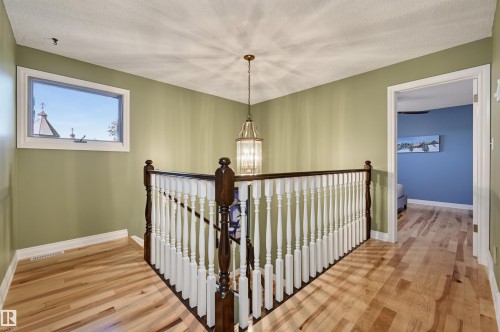 Hardwood flooring throughout, white painted railings with dark wood accents, and a contemporary chandelier - 30 Gariepy Crescent Nw, Edmonton, AB 