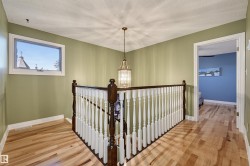 Hardwood flooring throughout, white painted railings with dark wood accents, and a contemporary chandelier - 