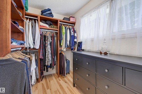 Custom closet organization system with wood-finish shelving and hanging rods - 30 Gariepy Crescent Nw, Edmonton, AB 