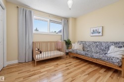 Hardwood flooring, painted walls, a double window with blinds, and a paneled door - 