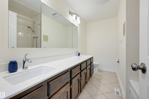 Double vanity with integrated sinks, chrome faucets, and dark wood-finish cabinetry - 30 Gariepy Crescent Nw, Edmonton, AB 