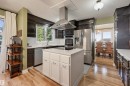 Kitchen featuring a white island with storage, stainless steel appliances, dark wood-finish cabinetry, and wood-finish flooring - 30 Gariepy Crescent Nw, Edmonton, AB 