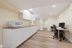 Wood-finish flooring throughout, white shaker-style cabinetry, wood-finish countertop, stainless steel sink, and recessed lighting - 
