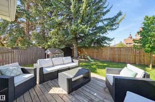 Expansive backyard featuring a wood deck, lawn area, mature trees, and privacy fencing - 30 Gariepy Crescent Nw, Edmonton, AB 