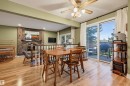 Hardwood-style flooring, brick-clad fireplace, white spindle railing, sliding glass doors to exterior, and a ceiling fan with light fixture - 30 Gariepy Crescent Nw, Edmonton, AB 