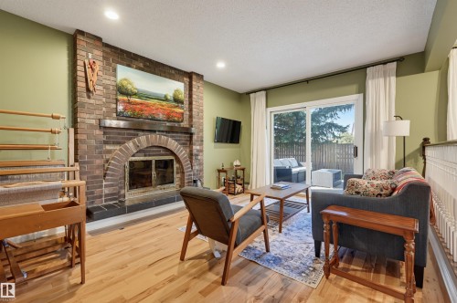 Brick fireplace with an arched firebox, wood-finish flooring, recessed lighting, and sliding glass patio doors - 30 Gariepy Crescent Nw, Edmonton, AB 