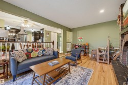 Hardwood flooring, brick fireplace with tile hearth, recessed ceiling lighting, and a ceiling fan in the kitchen area - 