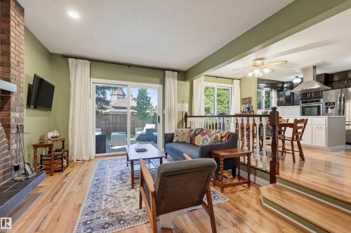 Hardwood flooring, brick fireplace, recessed lighting, sliding glass door, and staircase with wood banister - 30 Gariepy Crescent Nw, Edmonton, AB 