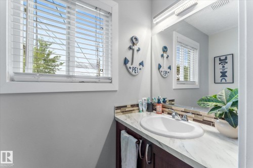 Built-in vanity with a single basin sink, chrome faucet, and a patterned tile backsplash - 16012 98 Avenue Nw, Edmonton, AB 