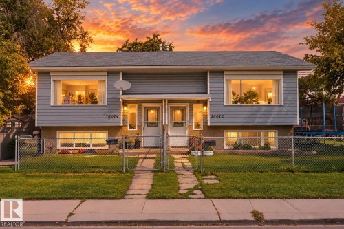 Duplex exterior featuring light gray siding, a dark gray roof, and prominent front windows - 16012 98 Avenue Nw, Edmonton, AB 