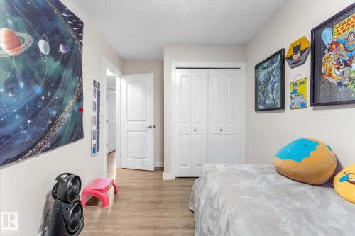 Wood-finish flooring, white bi-fold closet doors, and a white interior door with a silver-tone handle - 16012 98 Avenue Nw, Edmonton, AB 