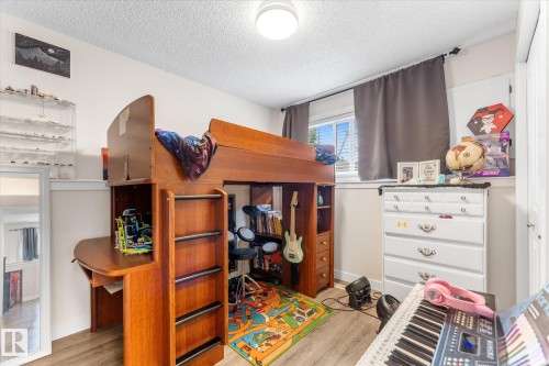 Room featuring wood-finish flooring, a double window with blinds, and a built-in wooden loft bed with an integrated desk - 16012 98 Avenue Nw, Edmonton, AB 