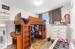 Room featuring wood-finish flooring, a double window with blinds, and a built-in wooden loft bed with an integrated desk - 