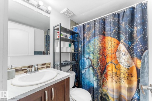 Vanity with integrated sink, wood-finish cabinetry, and mosaic tile backsplash - 16012 98 Avenue Nw, Edmonton, AB 