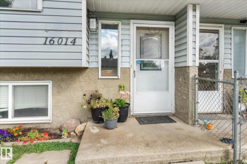 Entry featuring a white storm door, concrete porch, horizontal siding, and a textured stucco foundation - 16012 98 Avenue Nw, Edmonton, AB 