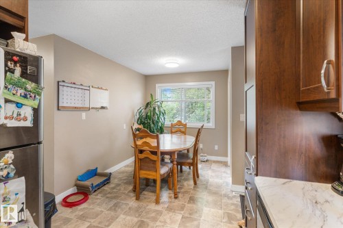 Kitchen featuring wood-finish cabinetry, light-toned countertops, and a stainless steel refrigerator - 16012 98 Avenue Nw, Edmonton, AB 