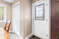 Entry door with decorative glass insert, paneled bifold closet door, wood-finish cabinetry, and tile flooring - 