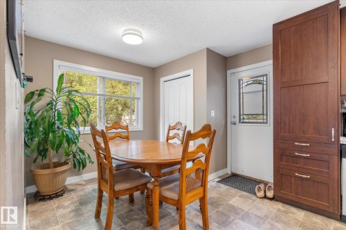 Tile flooring, white trim windows, white interior door with decorative glass insert, ceiling-mounted light fixture, and floor-to-ceiling wood-finish cabinetry - 16012 98 Avenue Nw, Edmonton, AB 