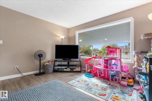 Spacious room featuring wood-finish flooring, a large window with blinds, and neutral-toned walls - 16012 98 Avenue Nw, Edmonton, AB 