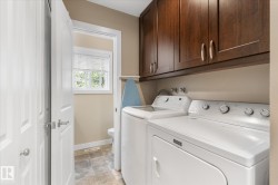 Laundry area with wood-finish cabinetry, a window with blinds, and tile flooring - 