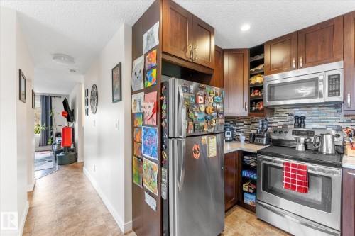 Kitchen featuring wood-finish cabinetry, stainless steel appliances, and a tiled backsplash - 16012 98 Avenue Nw, Edmonton, AB 