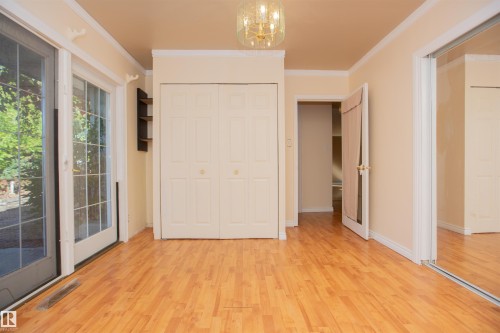 Wood-finish flooring, bi-fold closet doors, glass-paneled sliding door, built-in shelving, and a decorative ceiling light fixture - 13032 120 Street Nw, Edmonton, AB 