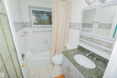 Jetted bathtub, vanity with stone-finish countertop, ceramic tile flooring, tiled shower surround, wall-mounted medicine cabinet - 13032 120 Street Nw, Edmonton, AB 