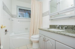 Built-in tub with adjacent toilet, single vanity with integrated sink, stone countertop, and wall-mounted medicine cabinet - 