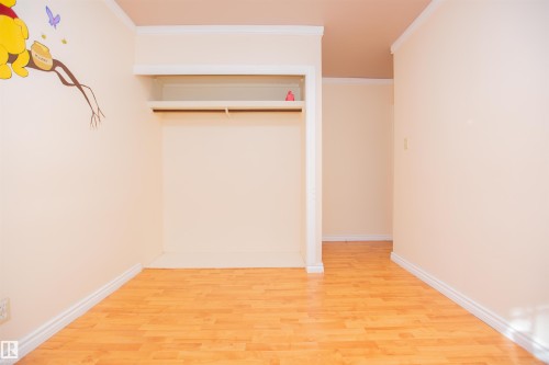 Wood-finish flooring with white trim, built-in open shelving, and a clothing rod - 13032 120 Street Nw, Edmonton, AB 