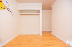 Wood-finish flooring with white trim, built-in open shelving, and a clothing rod - 