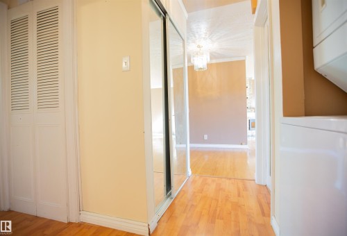 Wood-finish flooring throughout, louvered bi-fold door, mirrored sliding closet door, and a stacked washer/dryer unit - 13032 120 Street Nw, Edmonton, AB 
