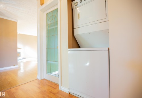 Hardwood flooring throughout, white interior trim, white-framed glass panel door, stackable laundry appliances - 13032 120 Street Nw, Edmonton, AB 
