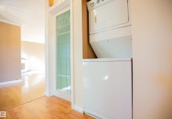 Hardwood flooring throughout, white interior trim, white-framed glass panel door, stackable laundry appliances - 