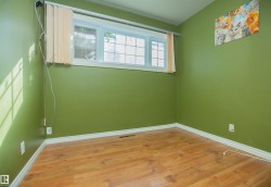 Wood-finish flooring with white trim, featuring a multi-pane window - 