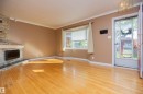 Hardwood flooring, stone-clad fireplace with mantel, bay window, crown molding, and decorative ceiling fixture - 13032 120 Street Nw, Edmonton, AB 