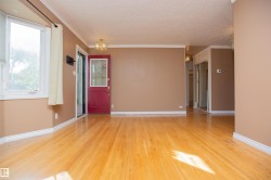 Hardwood flooring throughout, a red entry door with decorative glass, a bay window, and a built-in closet with mirrored sliding doors - 