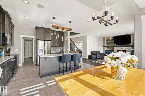 Open-concept living area with a stone-clad fireplace, integrated shelving, and recessed lighting - 2011 Genesis Lane, Stony Plain, AB 